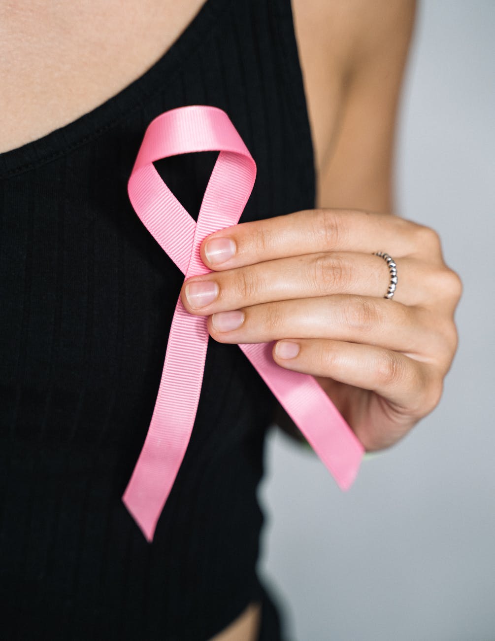 woman in black tank top holding pink ribbon 